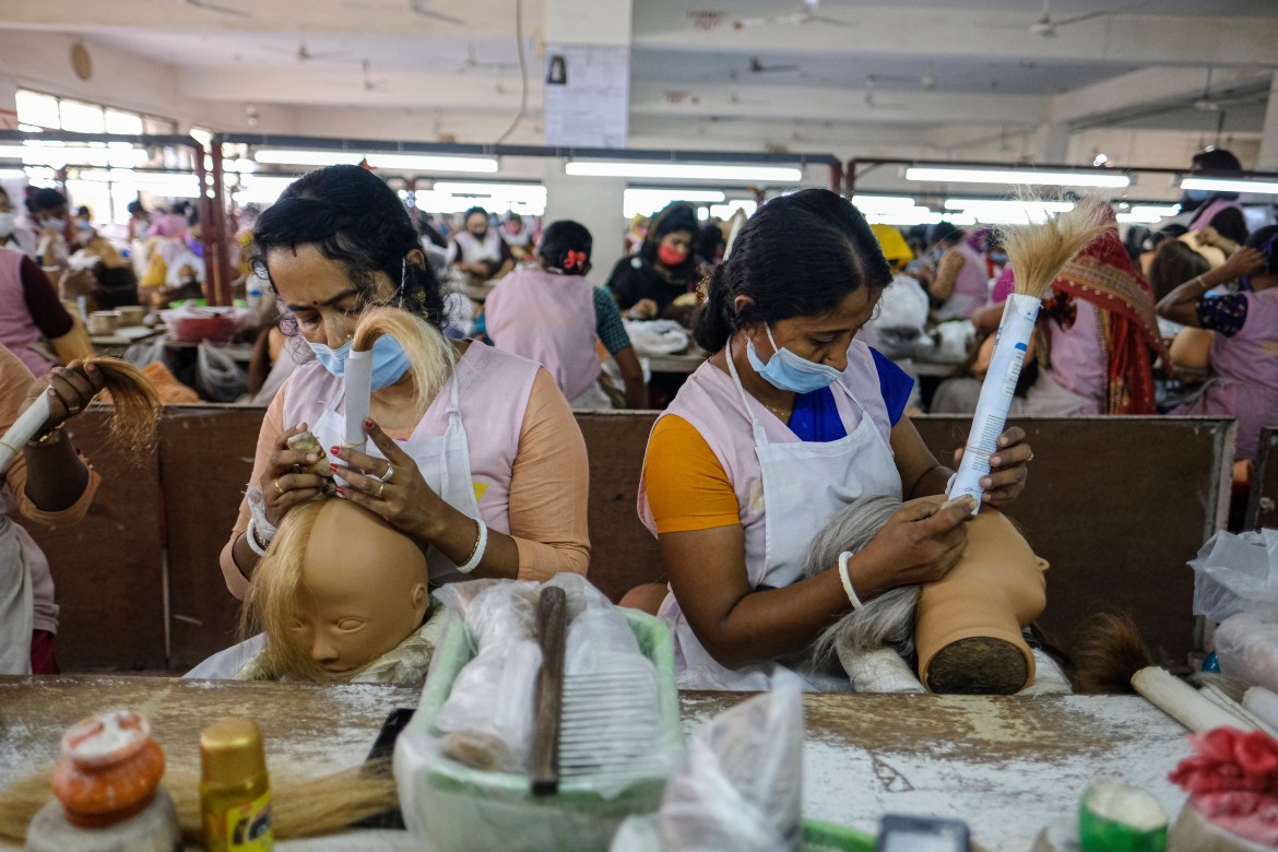 Workers set hair on mannequins at a factory inside an export processing zone in Mongla