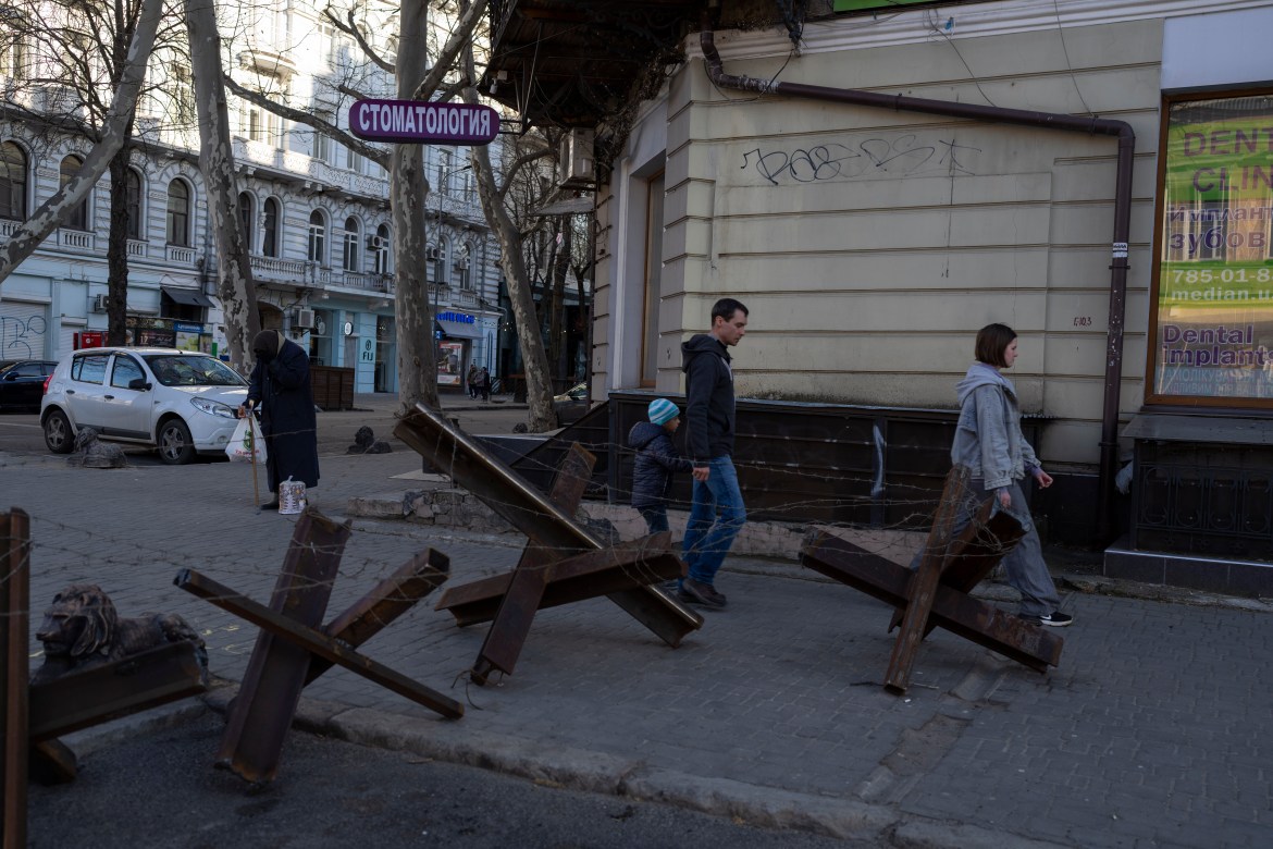 A family walks next to anti- tank barricades in Odesa