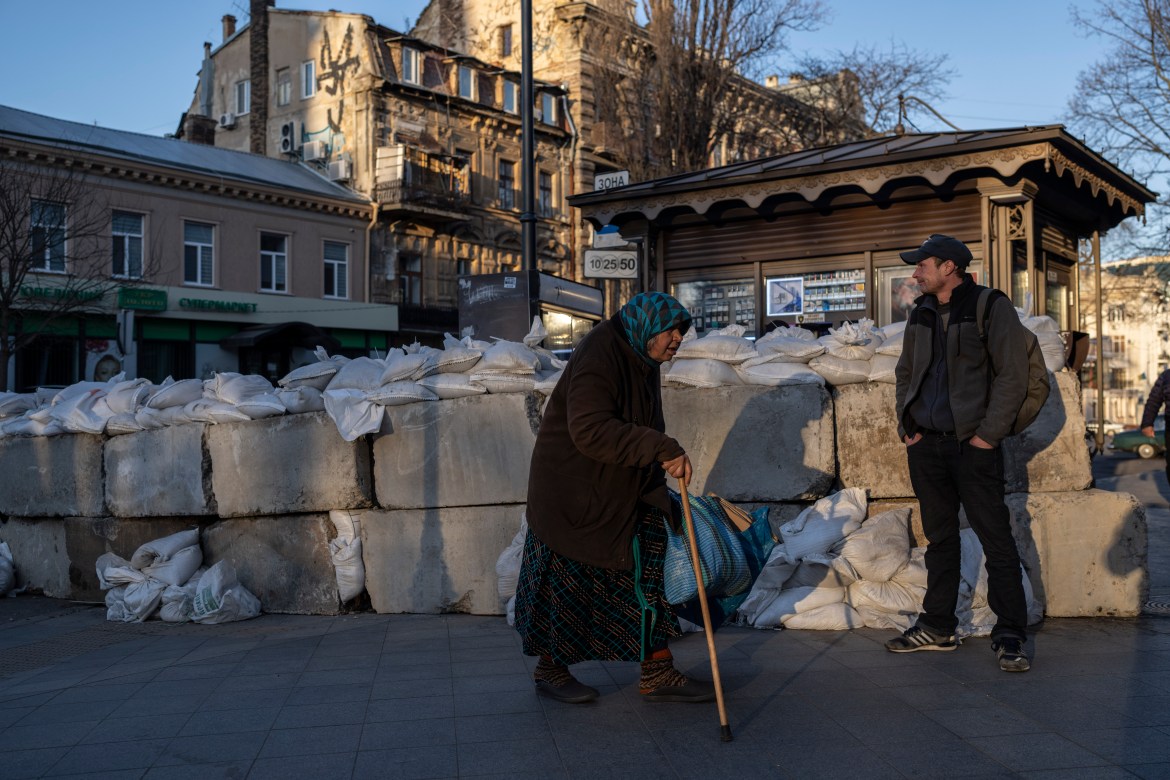 An elderly woman walks pass concrete blocks topped with sandbags at a street in Odesa, southern Ukraine,