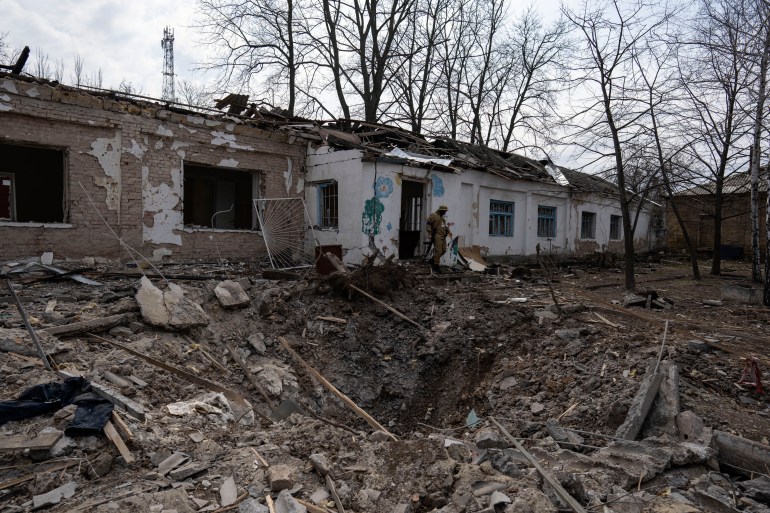 An Ukrainian soldier exits a Psychiatric hospital damaged by a Russian bombing earlier this week