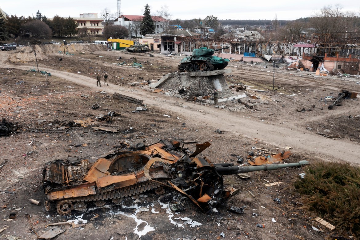 Local residents pass by a damaged Russian tank in the town of Trostyanets, east of capital Kyiv