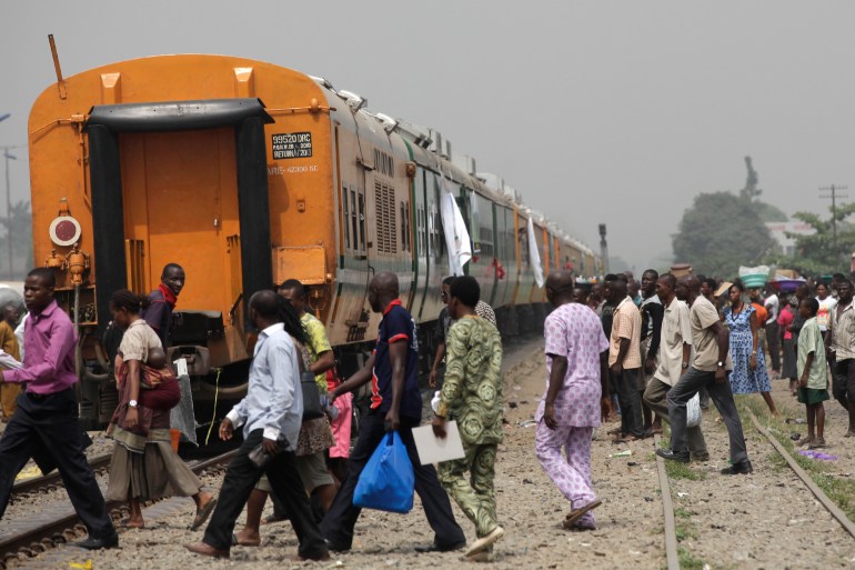 People cross the tracks as they wait for the train to move off as part of a newly inaugurated train service to Kano, Nigeria, in Lagos