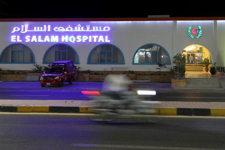 A motorcyclist rides past a police vehicle parked at the El Salam Hospital, after a fatal knife attack in Hurghada, Egypt