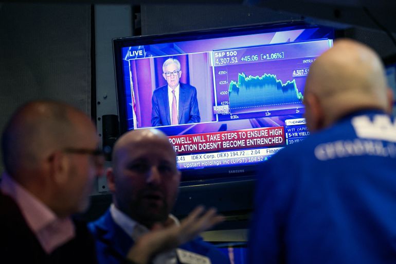 Traders work, as Federal Reserve Chair Jerome Powell is seen on a screen delivering remarks, at the New York Stock Exchange (NYSE) in New York City, U.S.