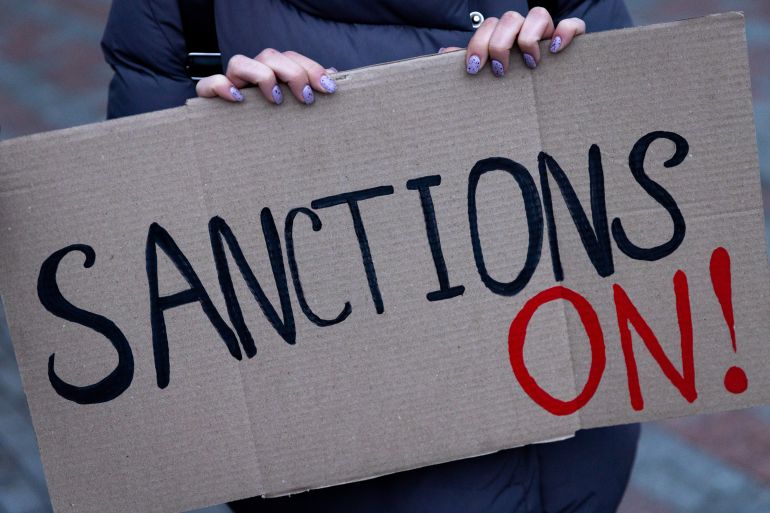 A protester holds sign that reads "sanctions on"
