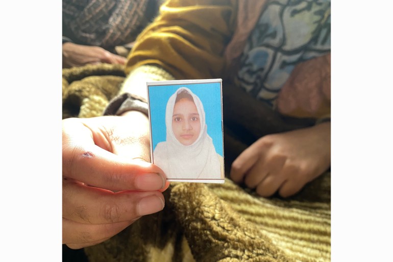 Rafiya's sister holding her picture. She was also wounded in the blast in which Rafiya was killed after suffering severe brain injury. [Rifat Fareed/Al Jazeera]