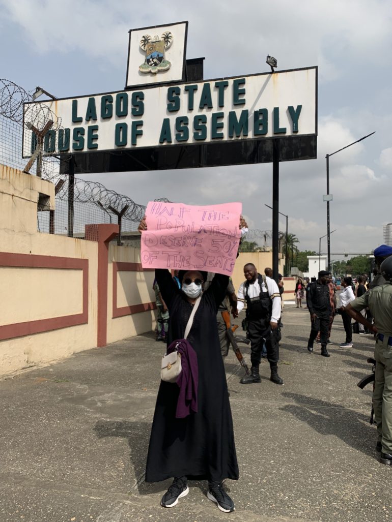 Kadaria Ahmed, a protester, holds aloft a cardboard outside the Lagos State House of Assembly on March 8, 2022.