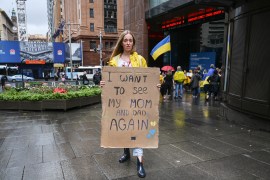 A woman holds an anti-war protest sign in Sydney, Australia