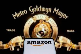 Smartphone with Amazon logo is seen in front of displayed MGM logo in this illustration