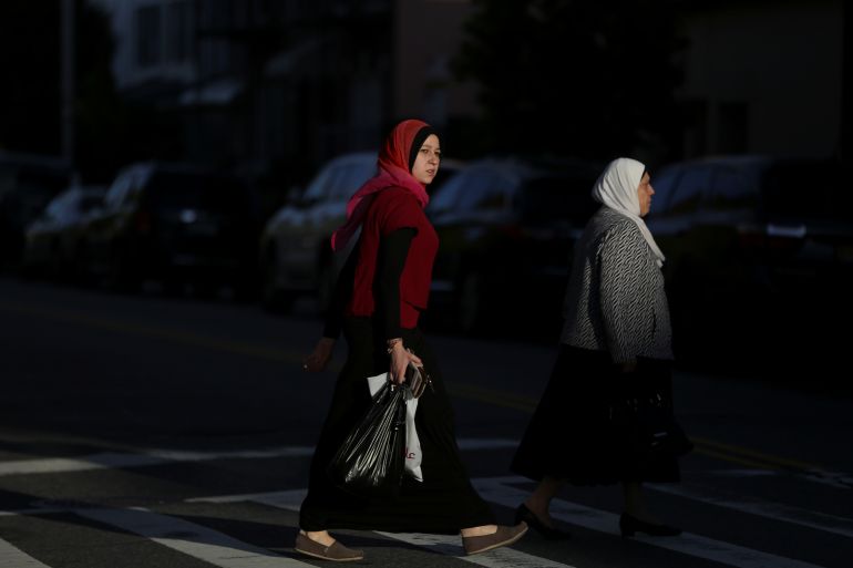 A photo of two Muslim American women crossing the street with shopping bags.