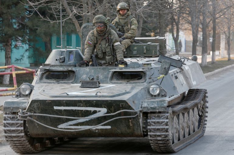 Russian troops are seen atop of an armoured vehicle with the symbols "Z" painted on its sides