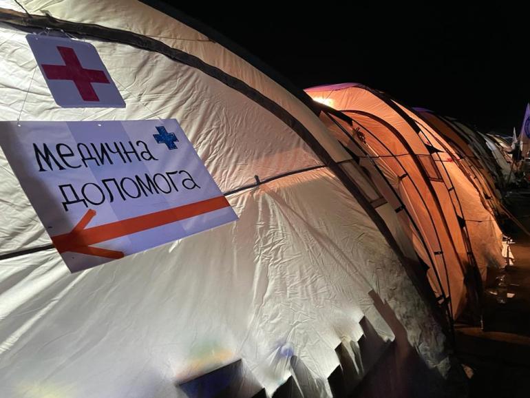 A photo of a tent with a red cross and a sign.