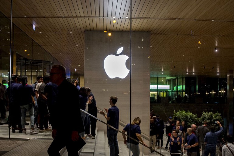 An Apple logo is illuminated as customers walk through the new Apple Inc. Michigan Avenue store during the store's opening in Chicago