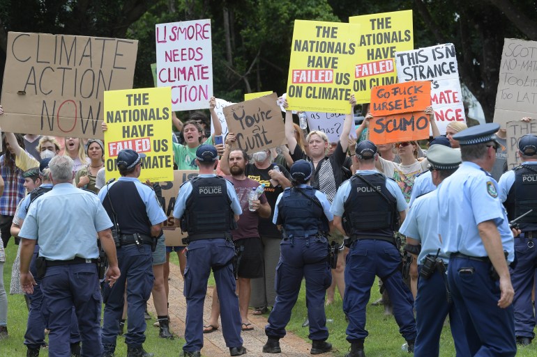 Climate activists protest as Prime Minister Scott Morrison holds a press conference following a visit to the Emergency Operations Centre in Lismore