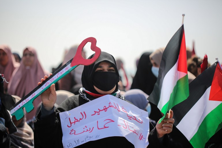 A Palestinain woman holds the flag and the return key. 