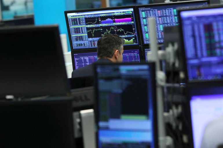 A trader works as screens show market data at CMC markets in London, Britain