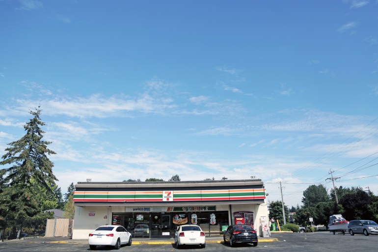 A 7-Eleven store in south Tacoma seen from the parking lot with three cars parked outside