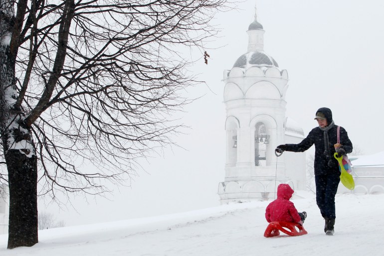 A woman walks with her baby under snow