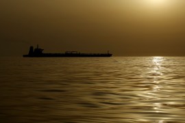 An oil tanker is silhouetted against the hazy sky