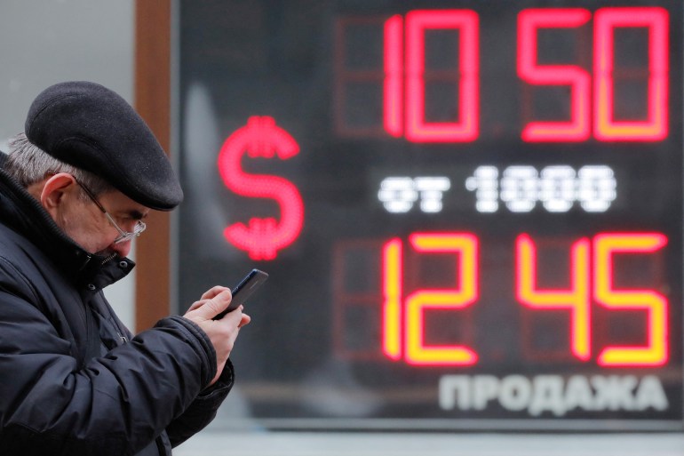 A man is seen near a board showing currency exchange rates in Russia's Saint Petersburg