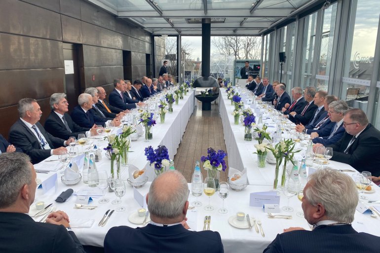 Photo showing all white, male CEO's having lunch at an event that is part of Munich Security Conference