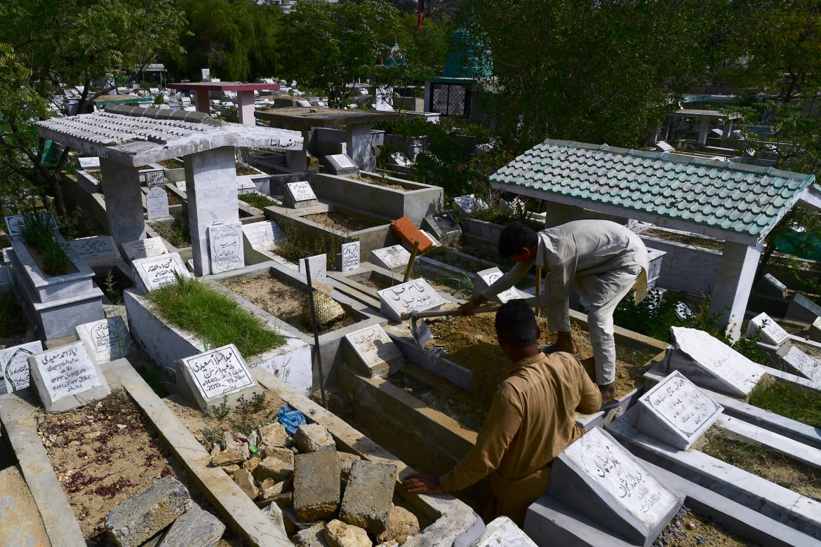 a gravedigger (R) makes a new grave at the Tariq Road graveyard