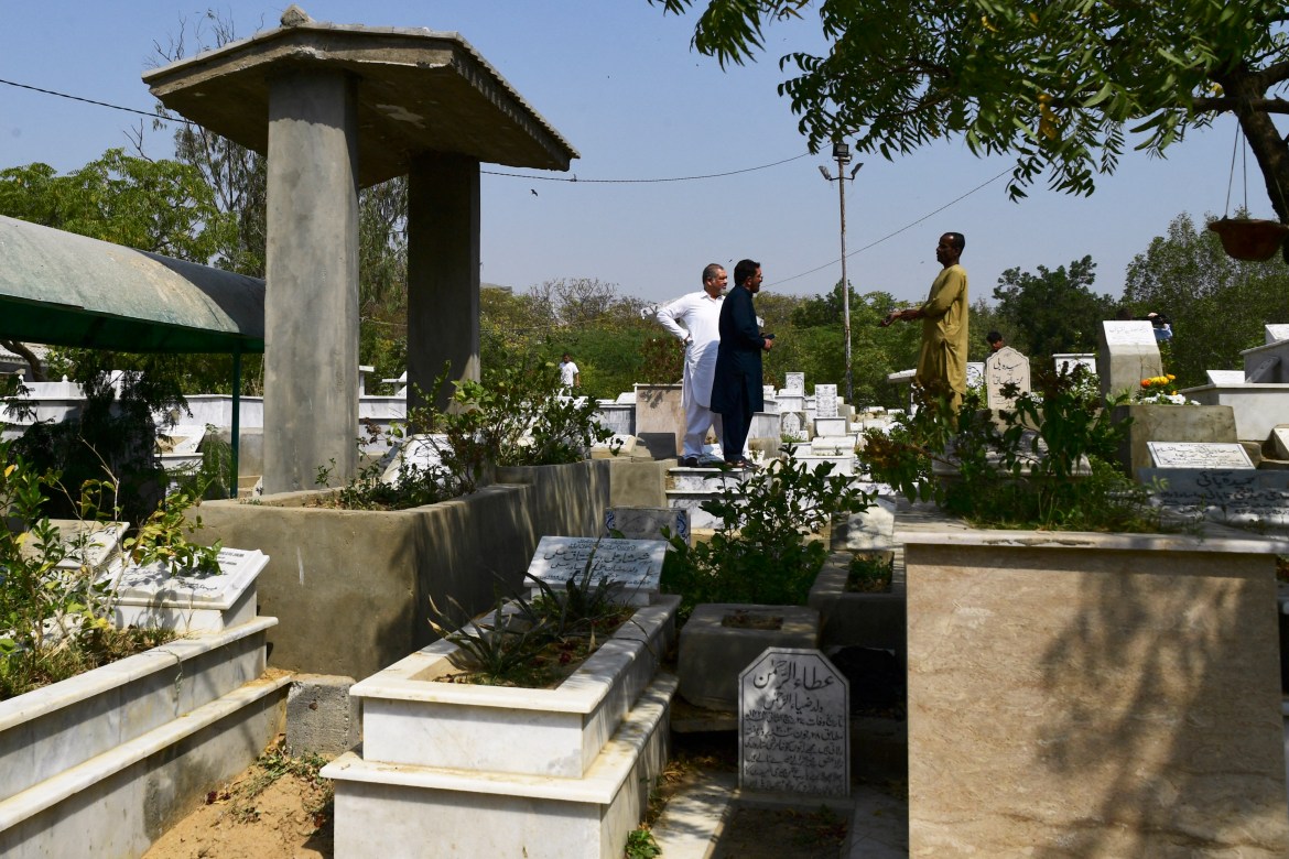 gravedigger Khalil Ahmed (R) speaks with relatives of a deceased person at the Tariq Road graveyard