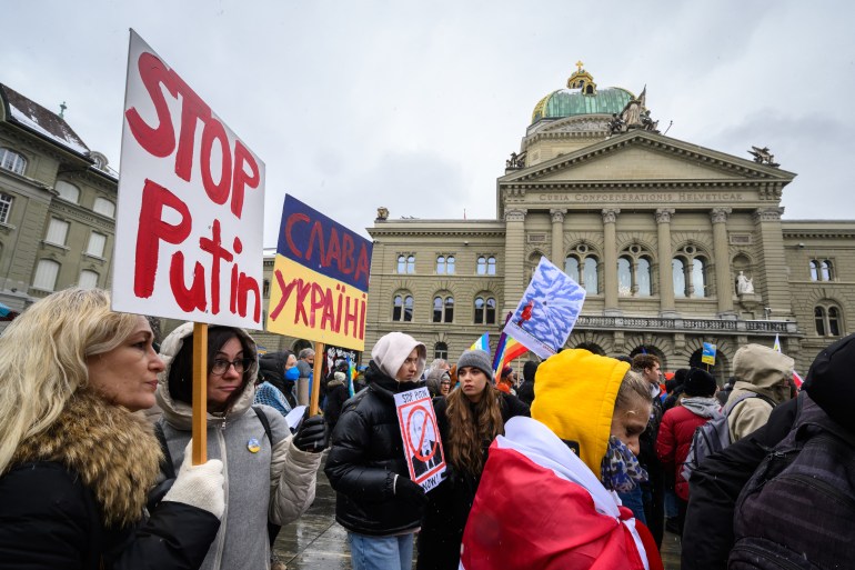 Women hold placards in front of the Swiss House of Parliament during a national demonstration for peace and against the war in Ukraine