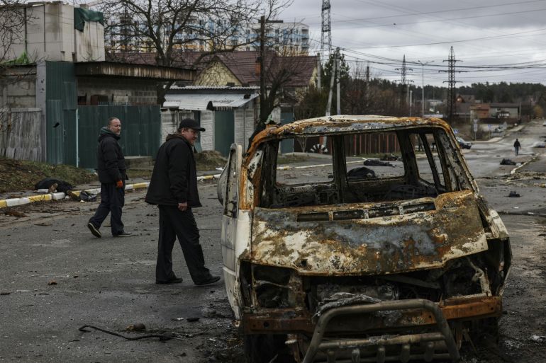 People walks on a street with several dead bodie in Bucha, Ukraine
