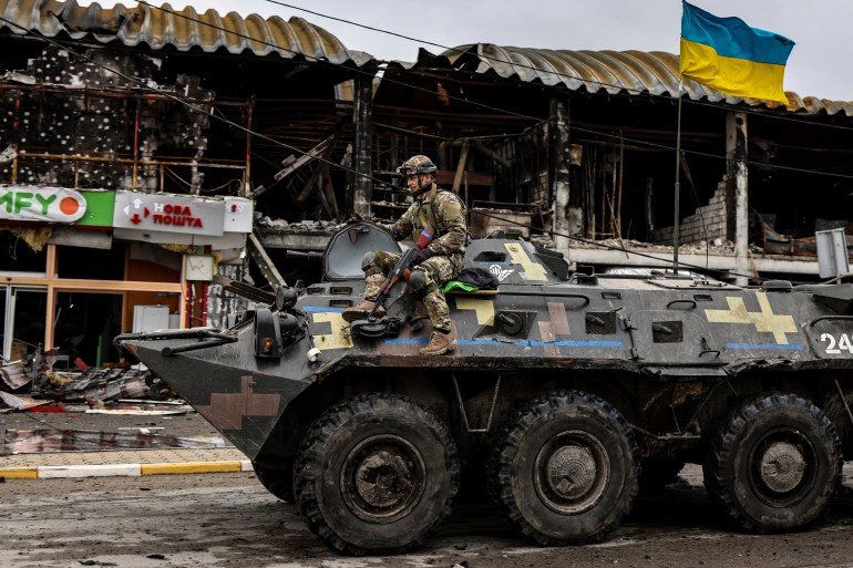 A Ukranian soldier patrols in an armoured vehicle a street in Bucha, northwest of Kyiv