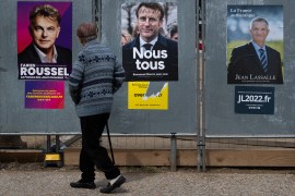 An elderly person looks at campaign posters for the French presidential elections