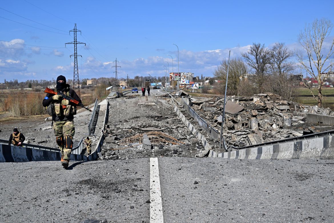 Ukrainian servicemen walk accross a destroyed bridge