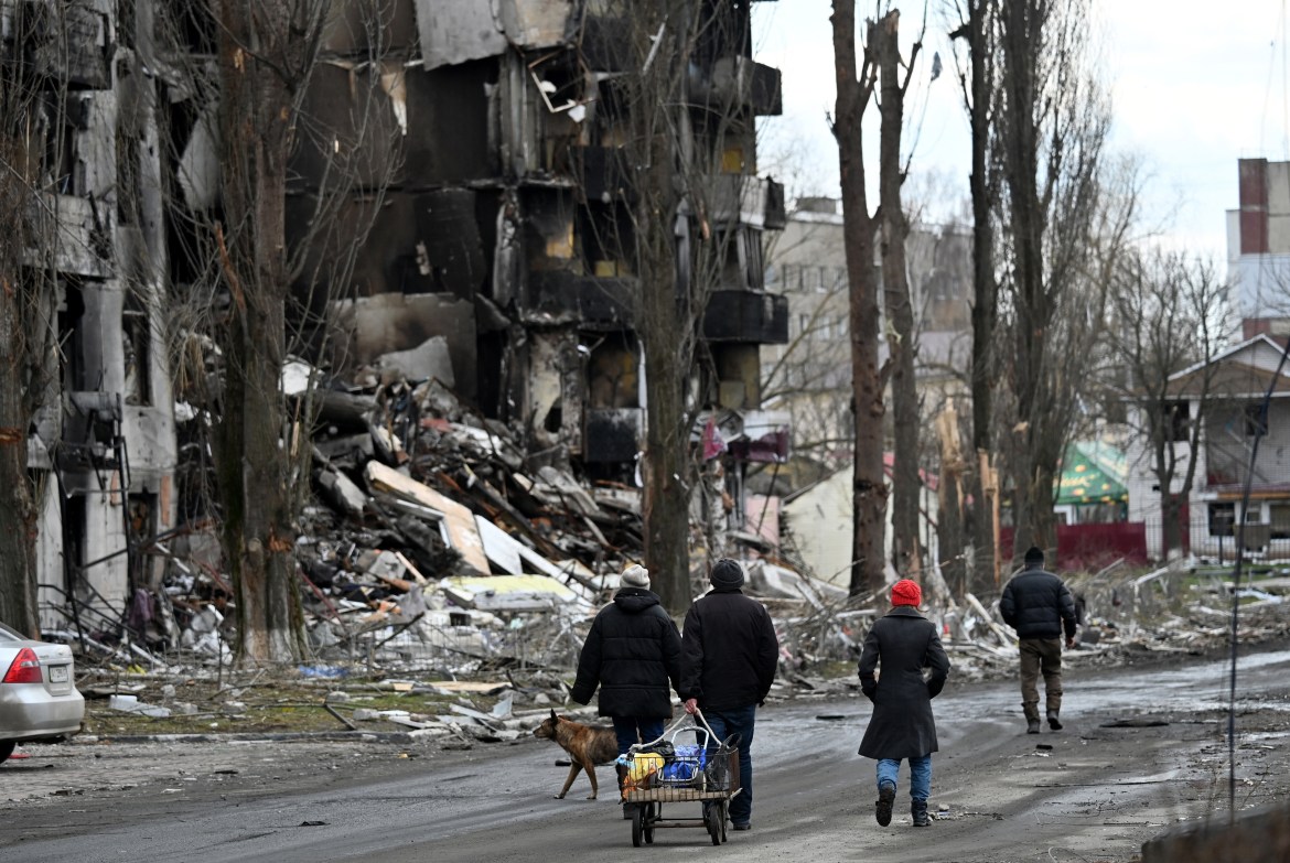 People walk past destroyed buildings in the town of Borodianka