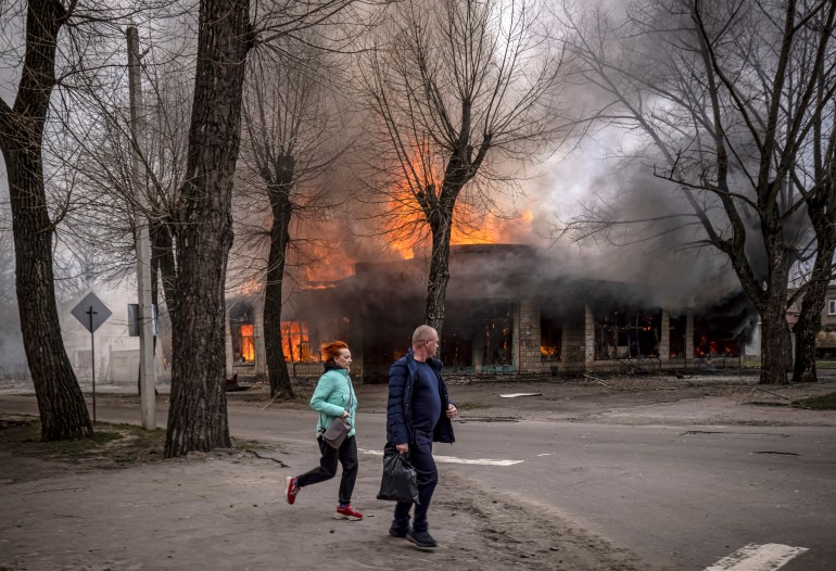 Residents run near a burning house.