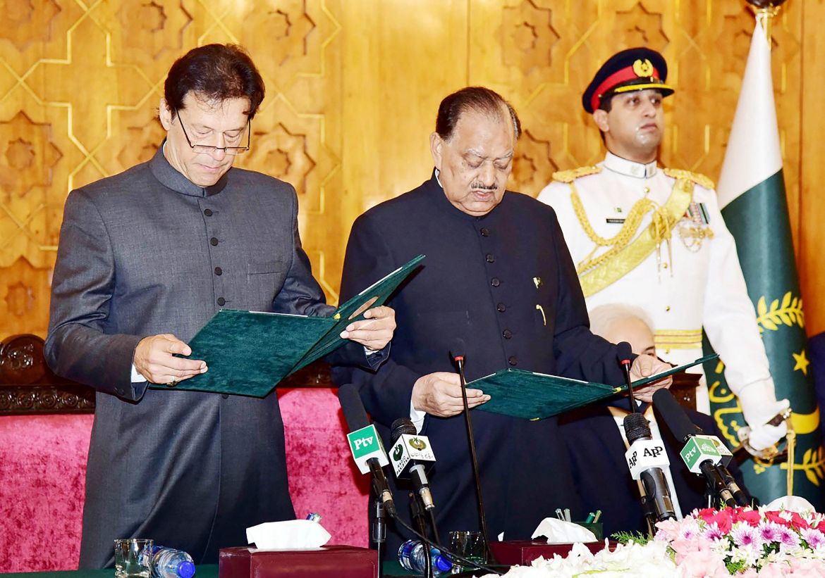 (FILES) This file handout photo taken on August 18, 2018 and released by Pakistan's Press Information Department (PID) shows Pakistan's President Mamnoon Hussain (C) taking an oath from newly appointed Prime Minister Imran Khan (L) during a ceremony in Islamabad.