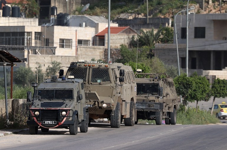 Israeli vehicles are positioned at the entrance of the Nur Shams Palestinian refugee camp