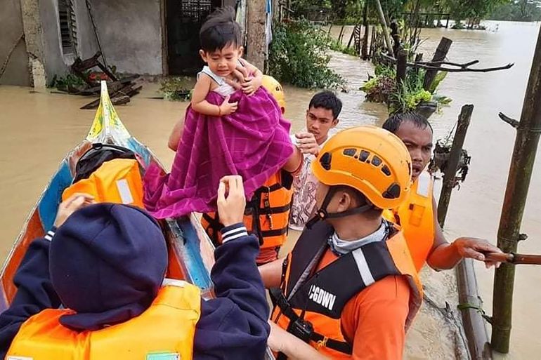 Coast guard personnel carry a boy as they evacuate local residents from their flooded homes in the town of Panay, Capiz province as heavy rains brought on by Tropical Storm Megi in the Philippines.