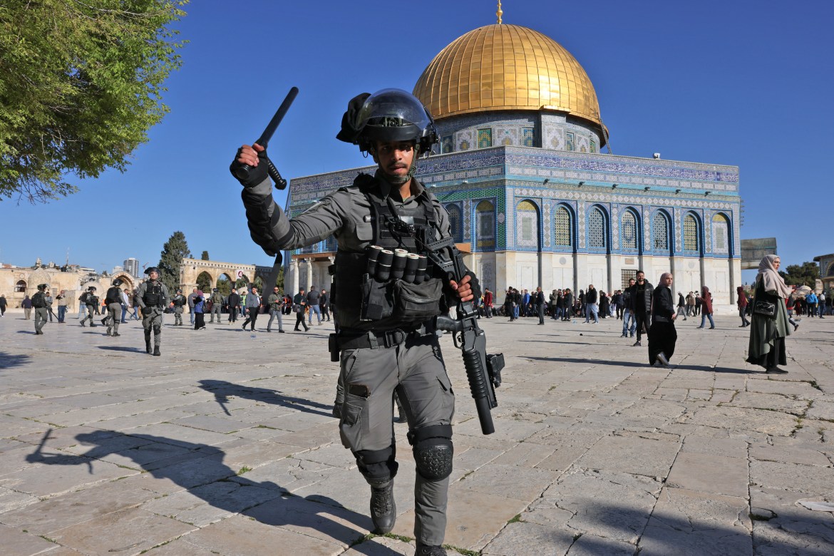 An Israeli police officers waves a baton in front of the Al-Aqsa compound.