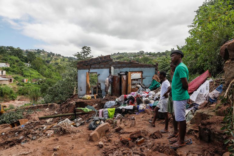 Neighbours stand next to the remains of a house at KwaNdengezi township outside Durban on April 15, 2022 where ten people are reportedly missing after their homes were swept away following the devastating rains and flooding.