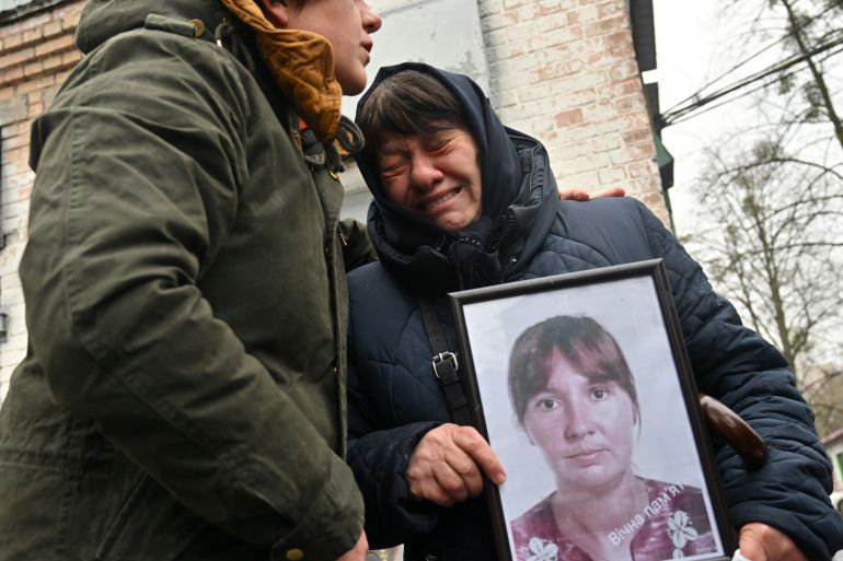 A woman cries as she holds a photograph of her adult daughter who was killed in Bucha in Ukraine