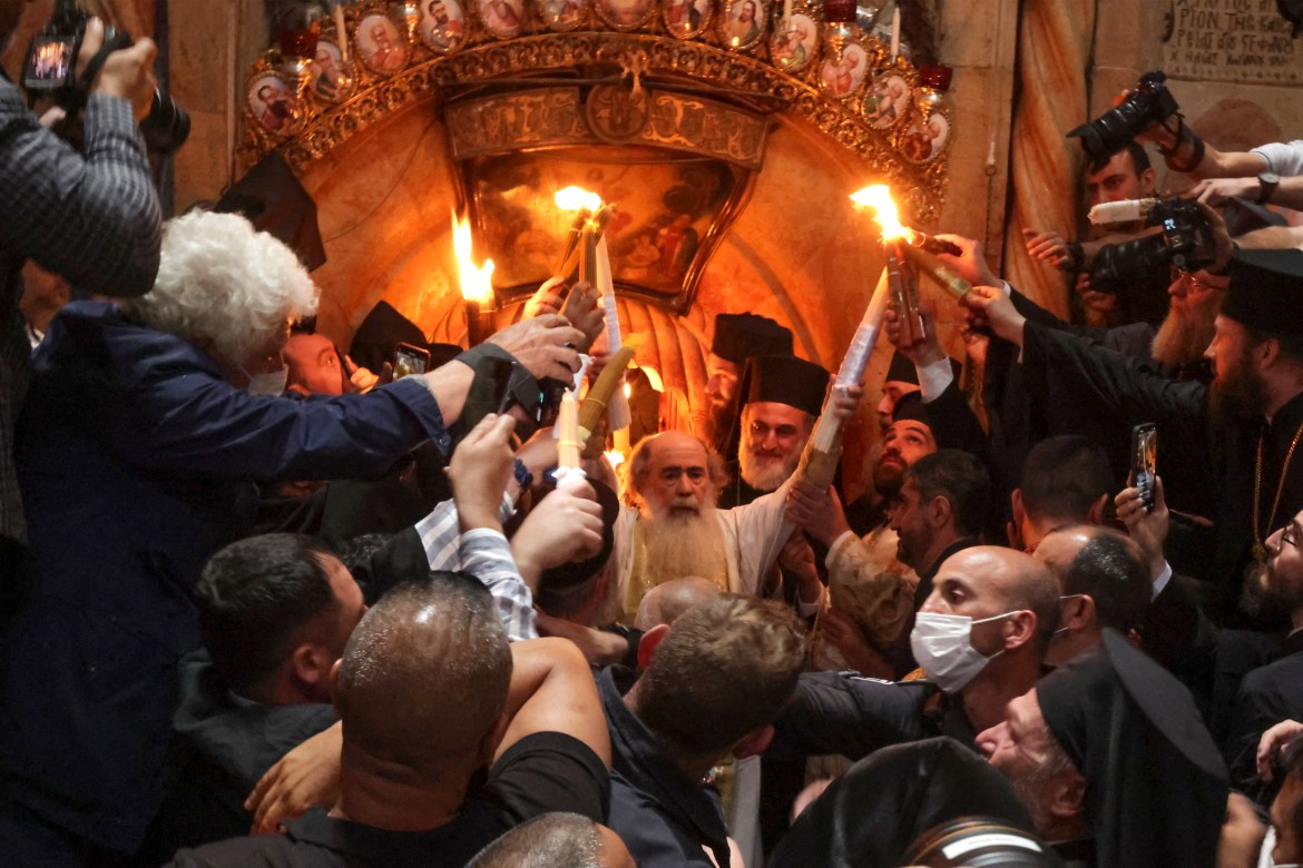 Greek Orthodox Patriarch of Jerusalem Theophilos III holds candles as Christians gather around the Edicule