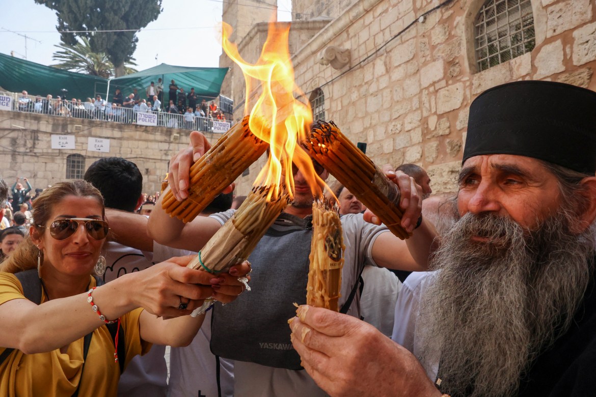 Worshippers light their candles from an Orthodox priest in the courtyard of Jerusalem's Holy Sepulchre church