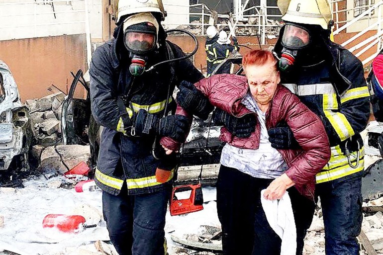 rescuers carrying a woman out of a damaged building