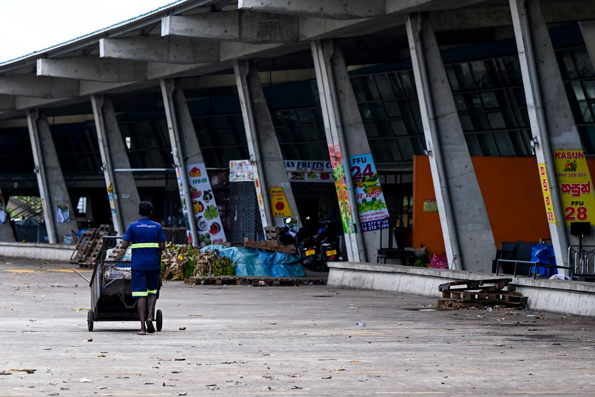 A worker stands pushes a cart at the deserted Manin market