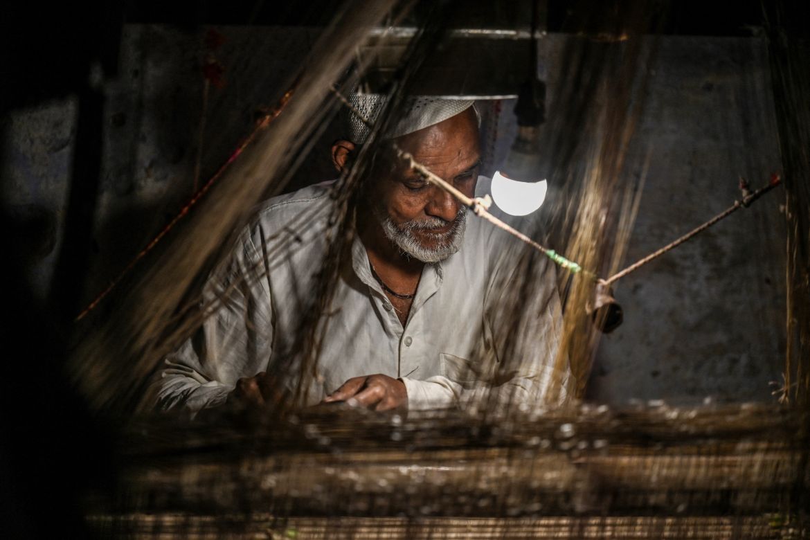 a worker uses a hand loom to weave a Banarasi silk sari at a workshop in Varanasi.