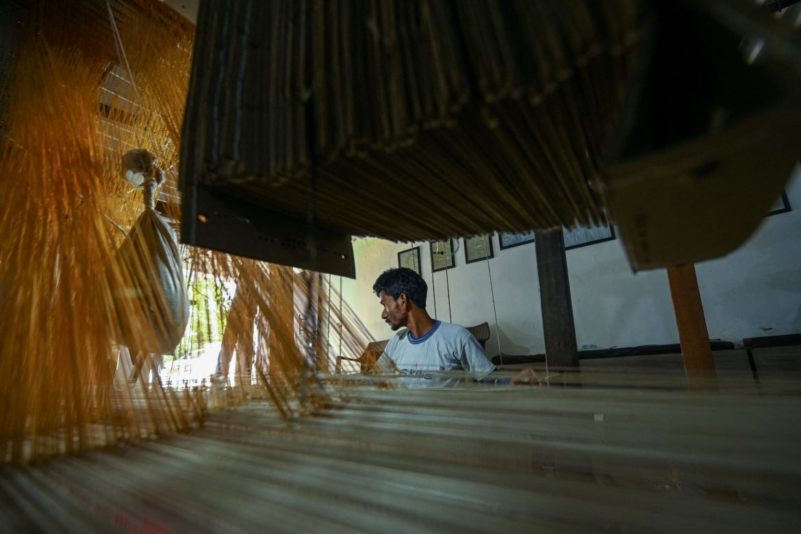 a worker uses a hand loom to weave a Banarasi silk sari