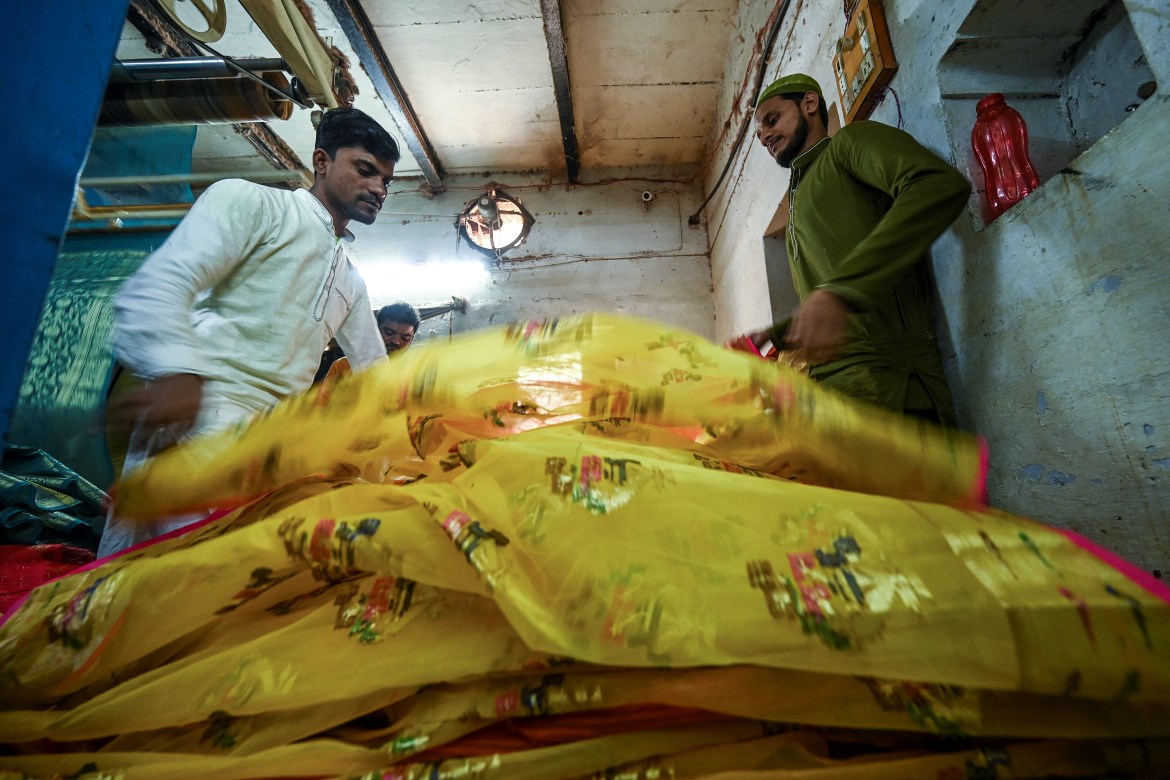 workers sort traditional Banarasi silk saris at a workshop in Varanasi