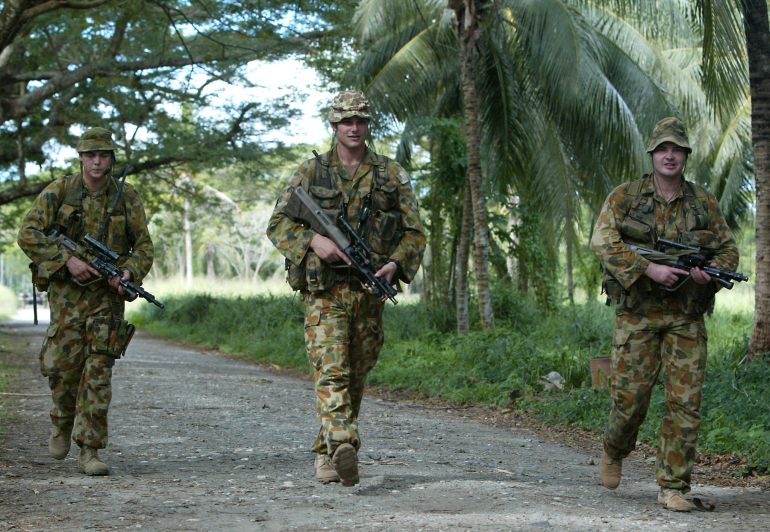 Três soldados australianos em patrulha nas Ilhas Salomão como parte da força multilateral RAMSI