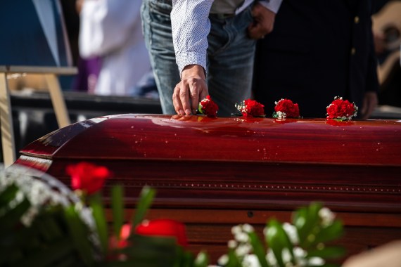 A person lays roses onto a coffin