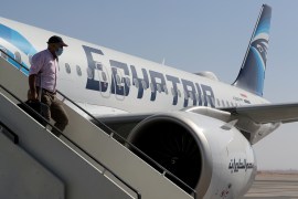 A traveller wearing a protective face mask disembarks from an EgyptAir plane.